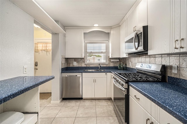 5623 80th St N Unit 415, Saint Petersburg, FL 33709 - kitchen featuring appliances with stainless steel finishes, decorative backsplash, dark countertops, light tile patterned floors, and white cabinetry