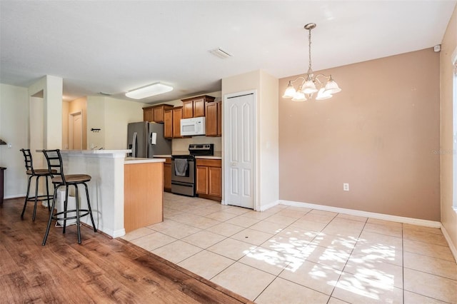 15420 Quail Woods Pl, Ruskin, FL 33573 - kitchen featuring stainless steel appliances, a kitchen bar, brown cabinetry, a chandelier, and light countertops