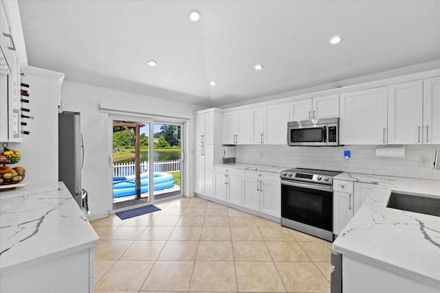 9831 Edmonton Dr, Land O Lakes, FL 34638 - kitchen with stainless steel appliances, tasteful backsplash, light stone countertops, white cabinets, and a water view
