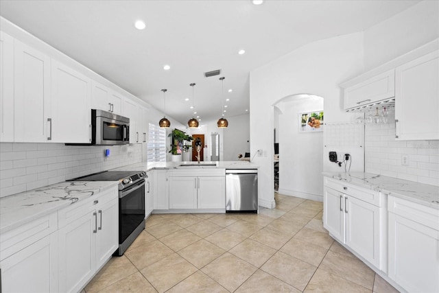 9831 Edmonton Dr, Land O Lakes, FL 34638 - kitchen with stainless steel appliances, plenty of natural light, arched walkways, vaulted ceiling, and tasteful backsplash
