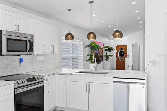 9831 Edmonton Dr, Land O Lakes, FL 34638 - kitchen featuring stainless steel appliances, a peninsula, white cabinetry, backsplash, and recessed lighting