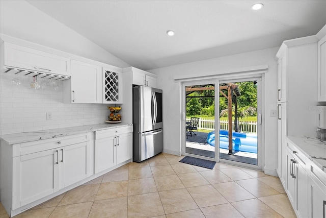 9831 Edmonton Dr, Land O Lakes, FL 34638 - kitchen featuring smart refrigerator, decorative backsplash, lofted ceiling, light stone countertops, and white cabinets