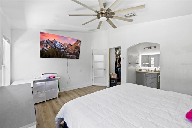 9831 Edmonton Dr, Land O Lakes, FL 34638 - bedroom with wood finished floors, arched walkways, connected bathroom, a spacious closet, and ceiling fan