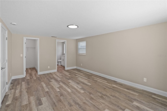 561 Golf And Sea Blvd, Apollo Beach, FL 33572 - unfurnished bedroom with light wood-style floors, a spacious closet, a closet, and connected bathroom