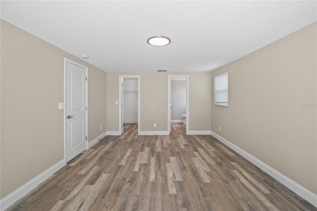 561 Golf And Sea Blvd, Apollo Beach, FL 33572 - unfurnished bedroom featuring wood finished floors, a spacious closet, and a closet