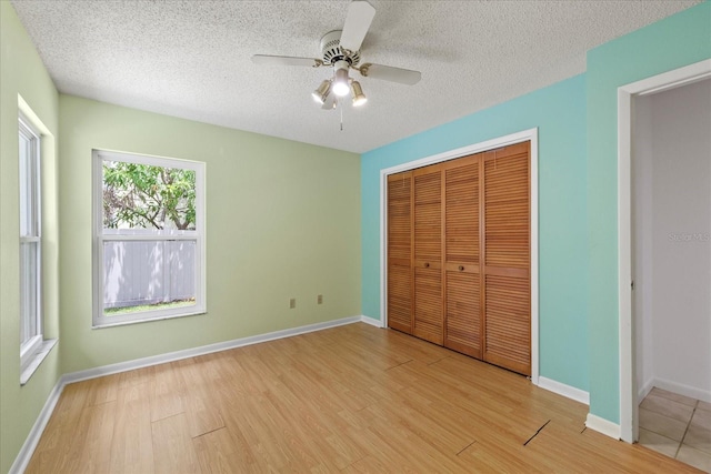 6706 Dunes Ln, Temple Terrace, FL 33617 - unfurnished bedroom featuring light wood-style floors, a closet, a textured ceiling, and ceiling fan