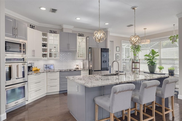 4147 Grandchamp Cir, Palm Harbor, FL 34685 - kitchen with appliances with stainless steel finishes, a chandelier, ornamental molding, backsplash, and glass insert cabinets