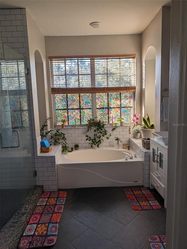 4147 Grandchamp Cir, Palm Harbor, FL 34685 - bathroom with healthy amount of natural light, a garden tub, a shower stall, and tile patterned flooring