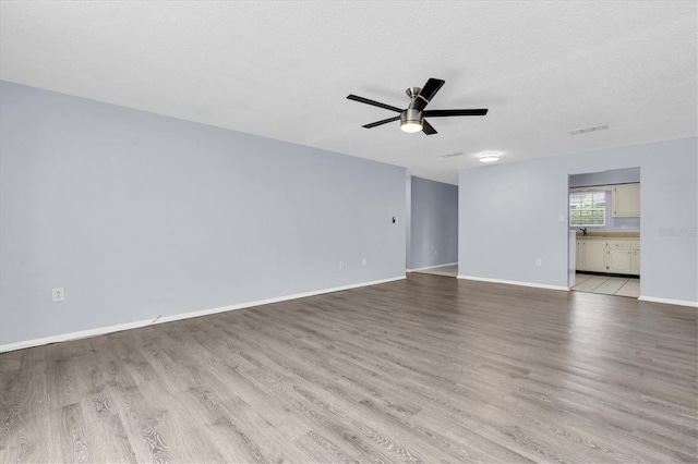 1706 Belleair Forest Dr Unit 146, Belleair, FL 33756 - empty room with light wood-style flooring, a ceiling fan, and a textured ceiling