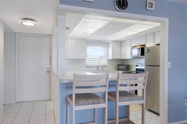 4775 Cove Cir Unit 803, Saint Petersburg, FL 33708 - kitchen with stainless steel appliances, light tile patterned floors, white cabinets, light countertops, and tasteful backsplash