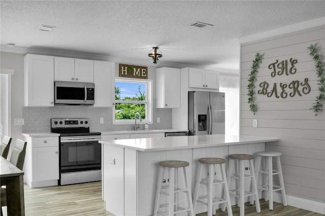3721 Casaba Loop, Valrico, FL 33596 - kitchen featuring appliances with stainless steel finishes, a textured ceiling, light countertops, backsplash, and a breakfast bar