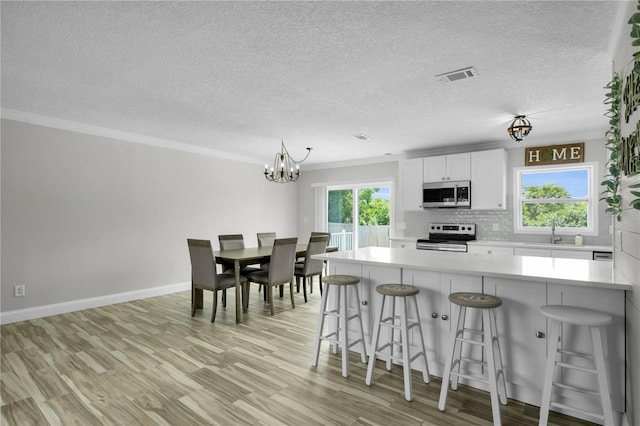 3721 Casaba Loop, Valrico, FL 33596 - kitchen with appliances with stainless steel finishes, plenty of natural light, a kitchen breakfast bar, backsplash, and ornamental molding