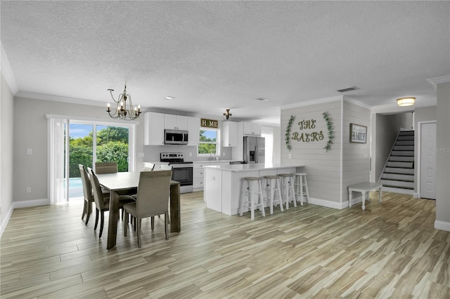 3721 Casaba Loop, Valrico, FL 33596 - dining area featuring a textured ceiling, plenty of natural light, stairs, light wood-type flooring, and crown molding