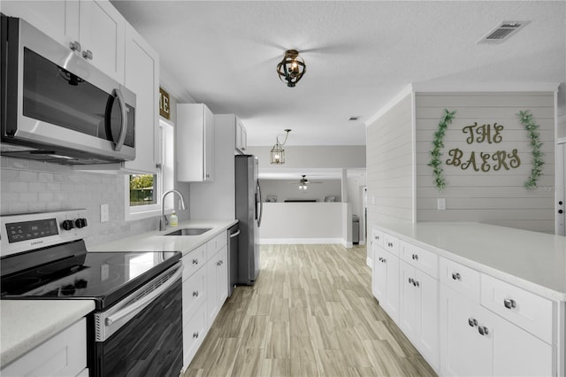 3721 Casaba Loop, Valrico, FL 33596 - kitchen with stainless steel appliances, tasteful backsplash, white cabinets, light countertops, and light wood-type flooring