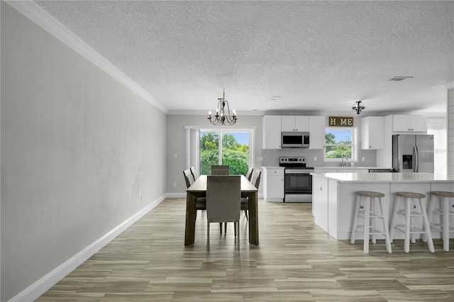 3721 Casaba Loop, Valrico, FL 33596 - dining room with a chandelier, plenty of natural light, a textured ceiling, crown molding, and light wood-style flooring