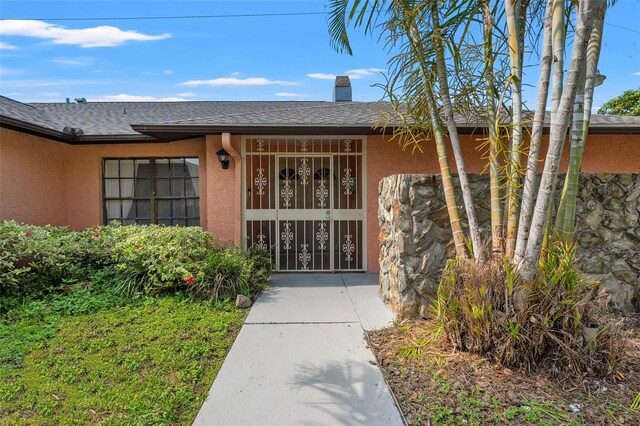 2708 W Bird St, Tampa, FL 33614 - entrance to property featuring stucco siding, roof with shingles, and a chimney