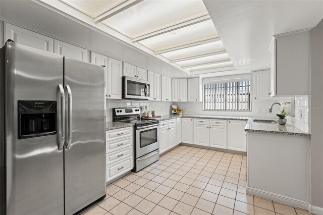 2708 W Bird St, Tampa, FL 33614 - kitchen featuring appliances with stainless steel finishes, light tile patterned floors, backsplash, and white cabinetry