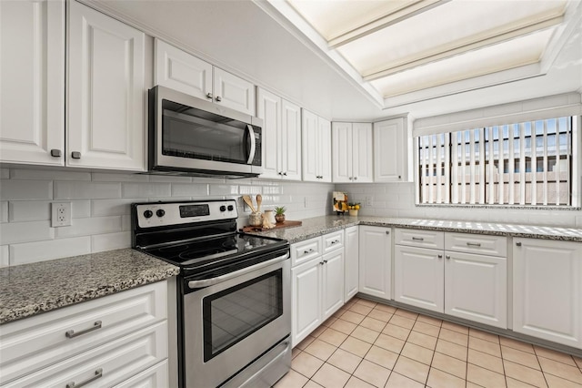 2708 W Bird St, Tampa, FL 33614 - kitchen with stainless steel appliances, decorative backsplash, light tile patterned floors, white cabinetry, and light stone counters