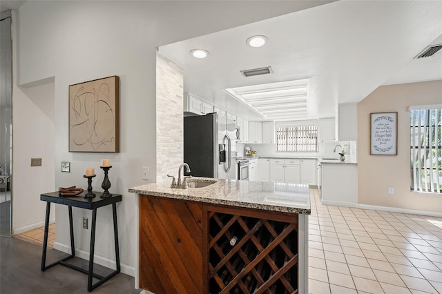 2708 W Bird St, Tampa, FL 33614 - kitchen with a peninsula, appliances with stainless steel finishes, white cabinetry, plenty of natural light, and recessed lighting