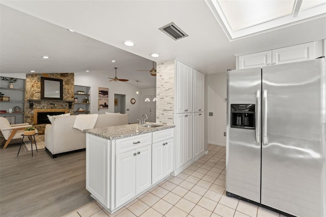 2708 W Bird St, Tampa, FL 33614 - kitchen featuring stainless steel refrigerator with ice dispenser, lofted ceiling, a stone fireplace, white cabinetry, and a ceiling fan