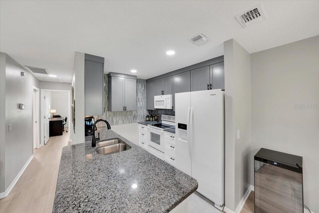 511 Foxglove Cir Unit B, Sun City Center, FL 33573 - kitchen with white appliances, light stone countertops, backsplash, light wood-style flooring, and gray cabinetry