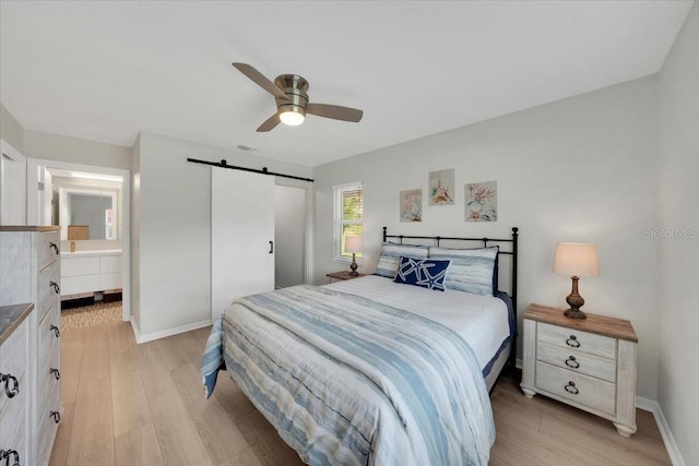 511 Foxglove Cir Unit B, Sun City Center, FL 33573 - bedroom with a barn door, light wood-style flooring, ceiling fan, and connected bathroom