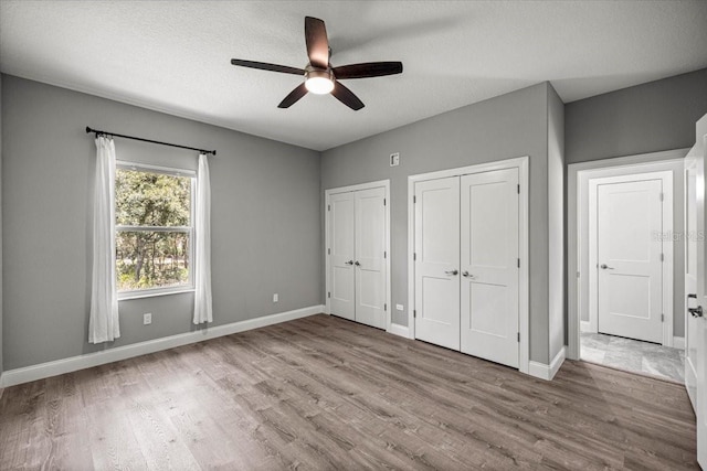 5352 W Corral Pl, Beverly Hills, FL 34465 - unfurnished bedroom with two closets, wood finished floors, a textured ceiling, and ceiling fan