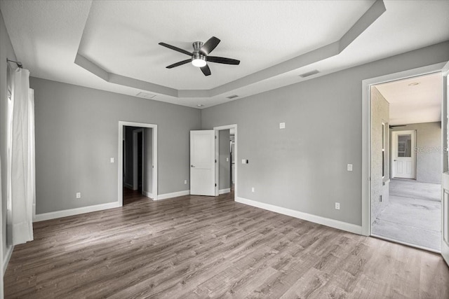 5352 W Corral Pl, Beverly Hills, FL 34465 - unfurnished bedroom with a tray ceiling, wood finished floors, ensuite bath, and a ceiling fan