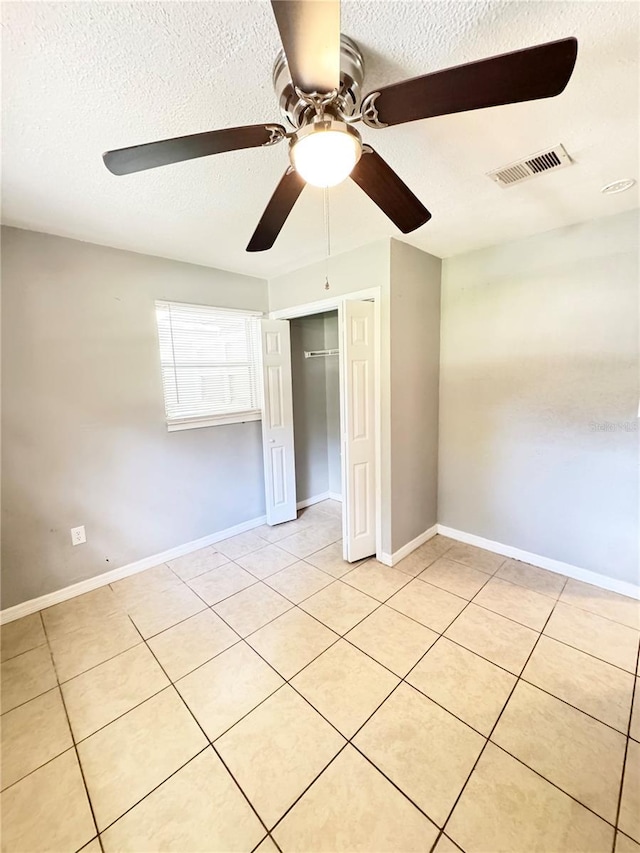 1507 W Le Compte Dr, Tampa, FL 33604 - unfurnished bedroom featuring a textured ceiling, a closet, light tile patterned flooring, and a ceiling fan