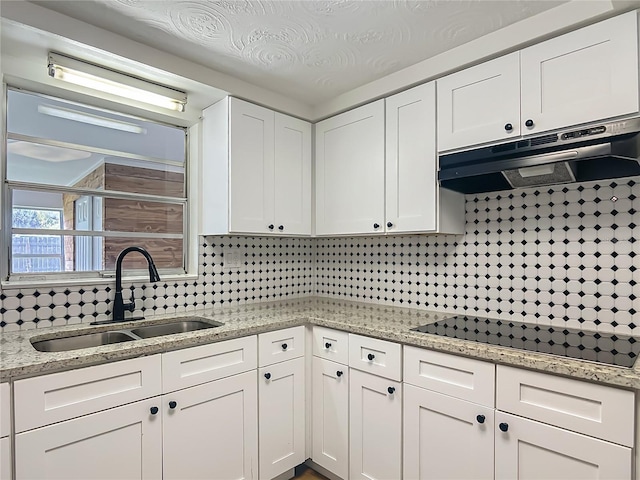 6632 Sierra Ter, New Port Richey, FL 34652 - kitchen with black electric cooktop, under cabinet range hood, white cabinetry, and backsplash