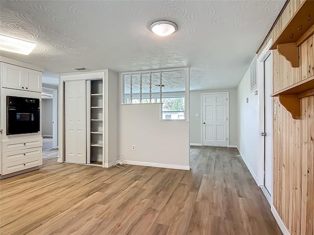 6632 Sierra Ter, New Port Richey, FL 34652 - kitchen with black oven, light wood-type flooring, a textured ceiling, and white cabinets