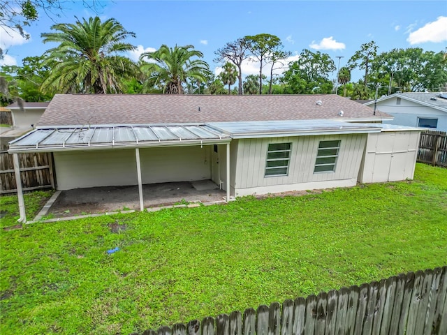 6632 Sierra Ter, New Port Richey, FL 34652 - back of house with a fenced backyard, roof with shingles, and a carport