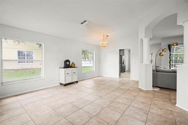 4948 Ridgemoor Cir, Palm Harbor, FL 34685 - unfurnished room with ornate columns, light tile patterned floors, healthy amount of natural light, and a textured ceiling