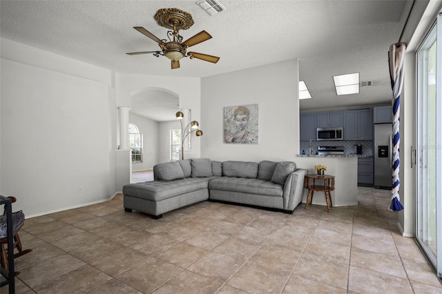 4948 Ridgemoor Cir, Palm Harbor, FL 34685 - living area with arched walkways, a textured ceiling, ceiling fan, and light tile patterned floors