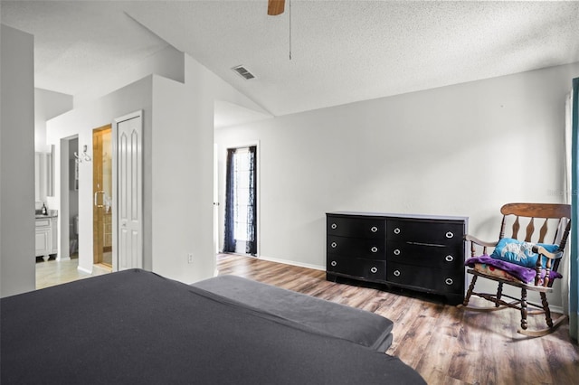 4948 Ridgemoor Cir, Palm Harbor, FL 34685 - bedroom with wood finished floors, vaulted ceiling, a textured ceiling, ensuite bathroom, and ceiling fan