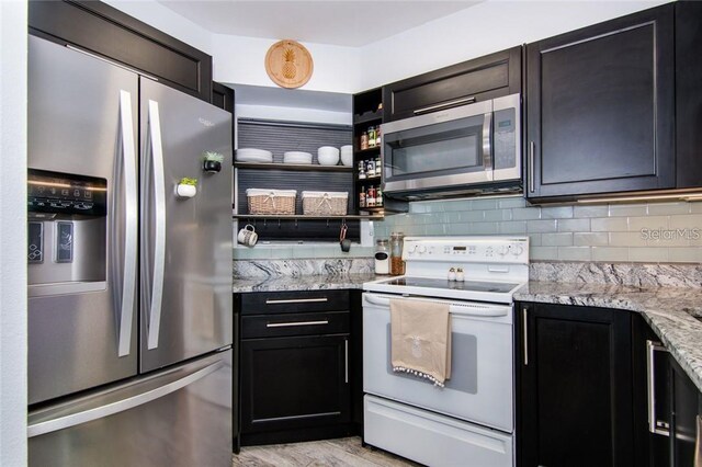 6932 Stones Throw Cir N Unit 7101, Saint Petersburg, FL 33710 - kitchen with stainless steel appliances, backsplash, light stone counters, and light wood finished floors