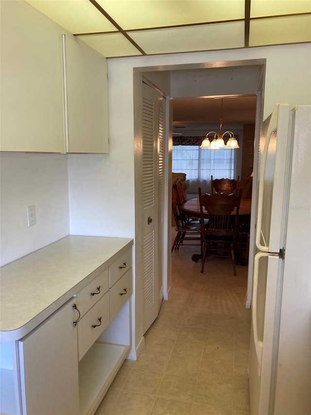 5623 80th St N Unit 314, Saint Petersburg, FL 33709 - kitchen featuring freestanding refrigerator, a chandelier, light countertops, white cabinets, and light tile patterned floors