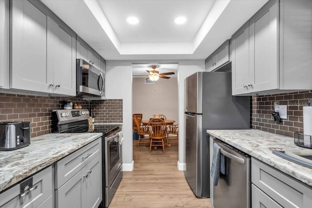 1485 Lakeview Rd Unit 2, Clearwater, FL 33756 - kitchen featuring appliances with stainless steel finishes, a tray ceiling, light wood-style floors, ceiling fan, and decorative backsplash