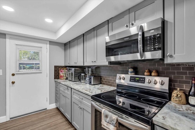 1485 Lakeview Rd Unit 2, Clearwater, FL 33756 - kitchen with appliances with stainless steel finishes, light wood-style floors, decorative backsplash, light stone countertops, and recessed lighting
