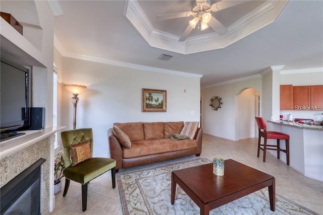 2733 Via Cipriani Unit 830B, Clearwater, FL 33764 - living room with arched walkways, a tray ceiling, crown molding, a ceiling fan, and a premium fireplace