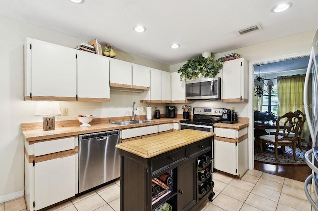 6642 Parson Brown Dr, Orlando, FL 32819 - kitchen featuring appliances with stainless steel finishes, butcher block countertops, white cabinets, light tile patterned floors, and recessed lighting