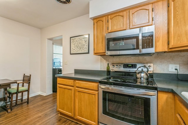 8014 27th Ave N, Saint Petersburg, FL 33710 - kitchen with stainless steel appliances, dark countertops, dark wood-style floors, and tasteful backsplash