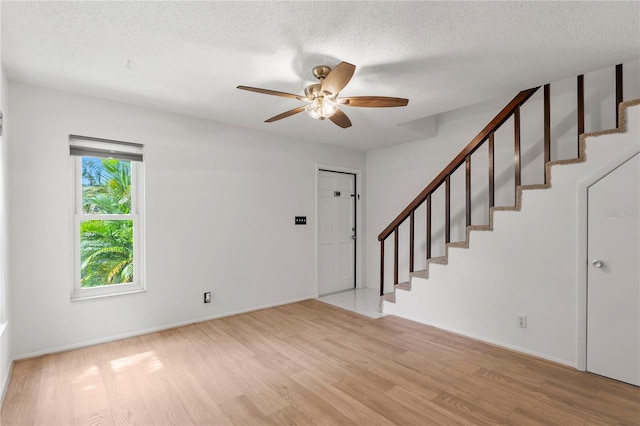 441 75th Ave N, Saint Petersburg, FL 33702 - unfurnished living room with stairs, light wood-type flooring, a ceiling fan, and a textured ceiling