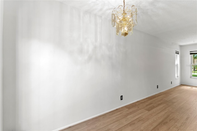 441 75th Ave N, Saint Petersburg, FL 33702 - empty room with light wood-style floors, a chandelier, and a textured ceiling