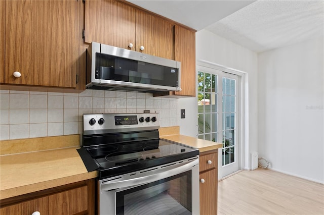 441 75th Ave N, Saint Petersburg, FL 33702 - kitchen featuring appliances with stainless steel finishes, light countertops, brown cabinets, light wood-style flooring, and backsplash