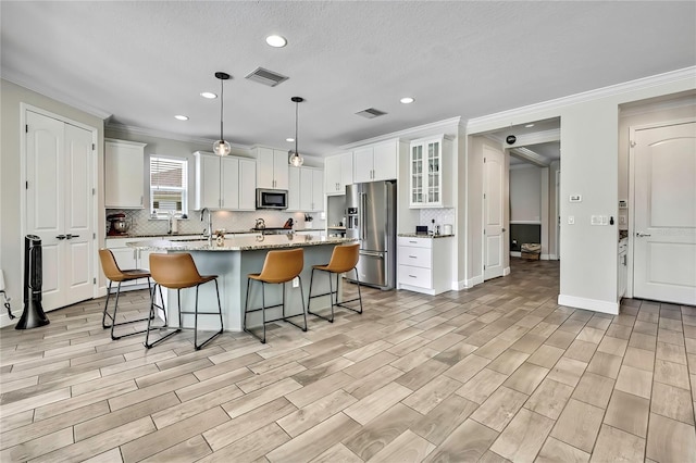 1669 Feather Grass Loop, Lutz, FL 33558 - kitchen with appliances with stainless steel finishes, ornamental molding, backsplash, an island with sink, and recessed lighting