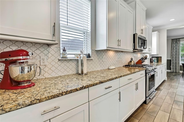 1669 Feather Grass Loop, Lutz, FL 33558 - kitchen with appliances with stainless steel finishes, white cabinets, tasteful backsplash, light stone countertops, and crown molding