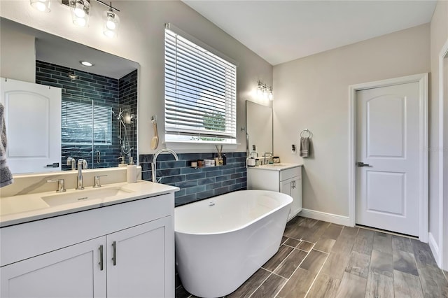 1669 Feather Grass Loop, Lutz, FL 33558 - full bathroom featuring two vanities, tiled shower, a soaking tub, wood finished floors, and tasteful backsplash