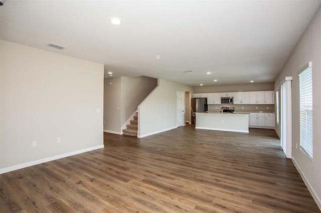 1229 Tidal St, Haines City, FL 33844 - unfurnished living room with stairs, dark wood-type flooring, recessed lighting, and plenty of natural light