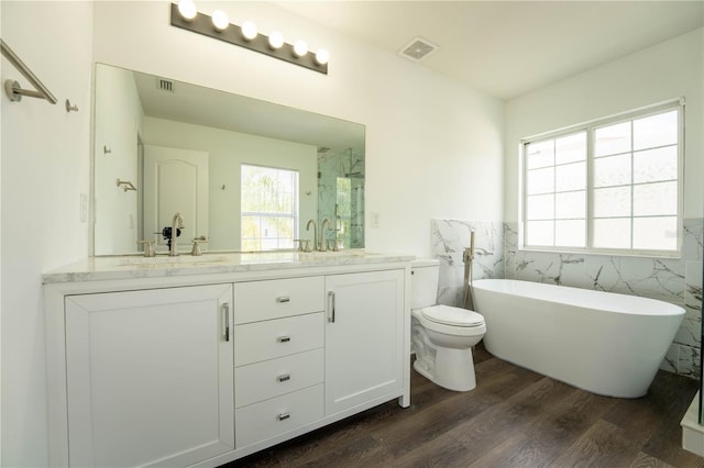 9110 Lantern Oak Way, Land O Lakes, FL 34638 - full bathroom featuring double vanity, tile walls, wood finished floors, a freestanding bath, and wainscoting